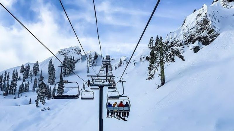 A ski lift carries people up a snowy mountain.