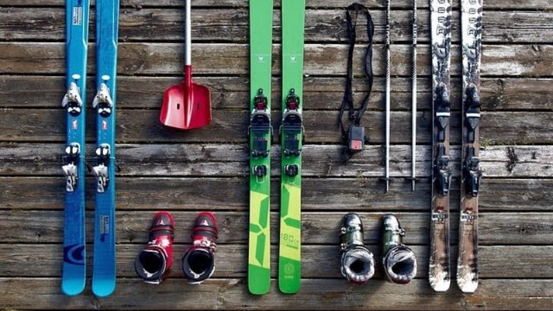 Ski gear is neatly arranged on a wooden deck.