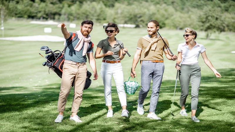 A group of friends walking with golf equipment, hanging out together on one of the beautiful Alta golf courses on a sunny day.