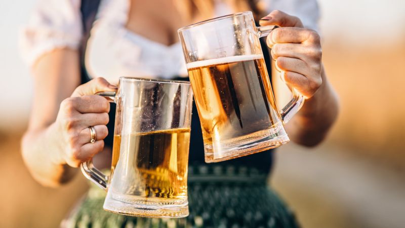 woman holding two mugs of beer in her hands for Oktoberfest