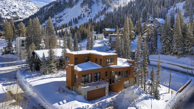 Modern mountain home surrounded by snow-covered trees in Alta, Utah.